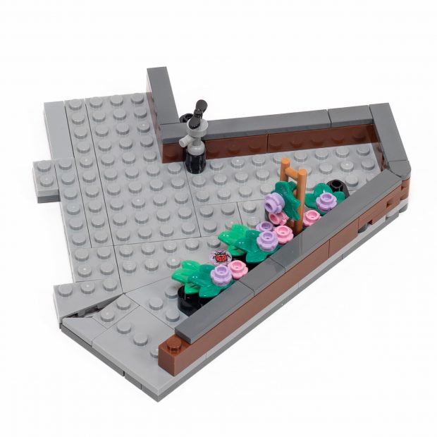 The roof of the smaller building has a low wall and some planters.